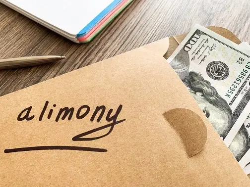 Brown envelope with money in it and the word alimony written on the envelope